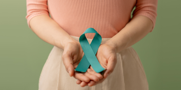 women with her hand together in front with a blue ribbon for cancer awareness in her hands