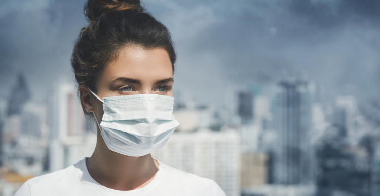 Women wearing a face mask to protect her from the air pollution happening in the background