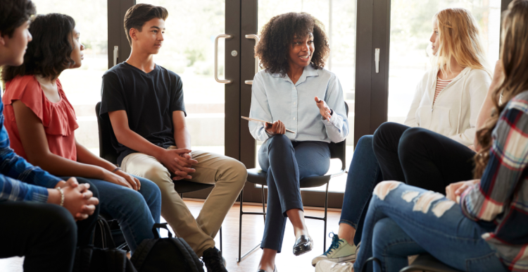 group of young people sitting on chairs in a circle having a conversation