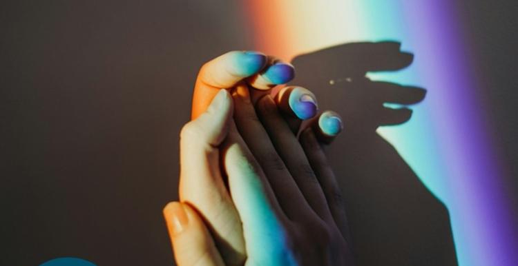 hands holding with a rainbow reflection on them
