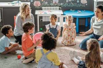 children in a circle with two adults playing games