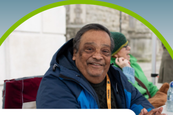Front page of annual report - Image of man sitting at desk smiling towards the viewer