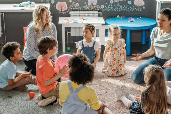 children in a circle with two adults playing games