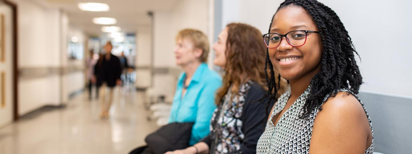 Woman sitting on a chair in a hospital corridor smiling to camera